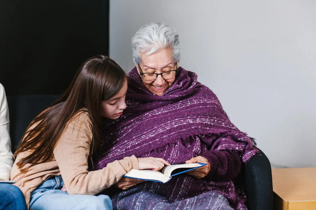 Elderly woman and young girl reading a book together.