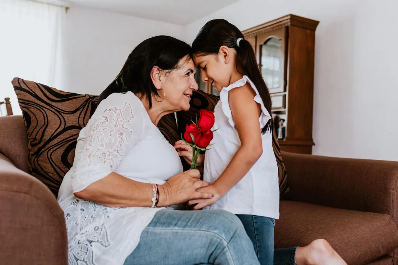 Elderly woman and young girl holding flowers together.