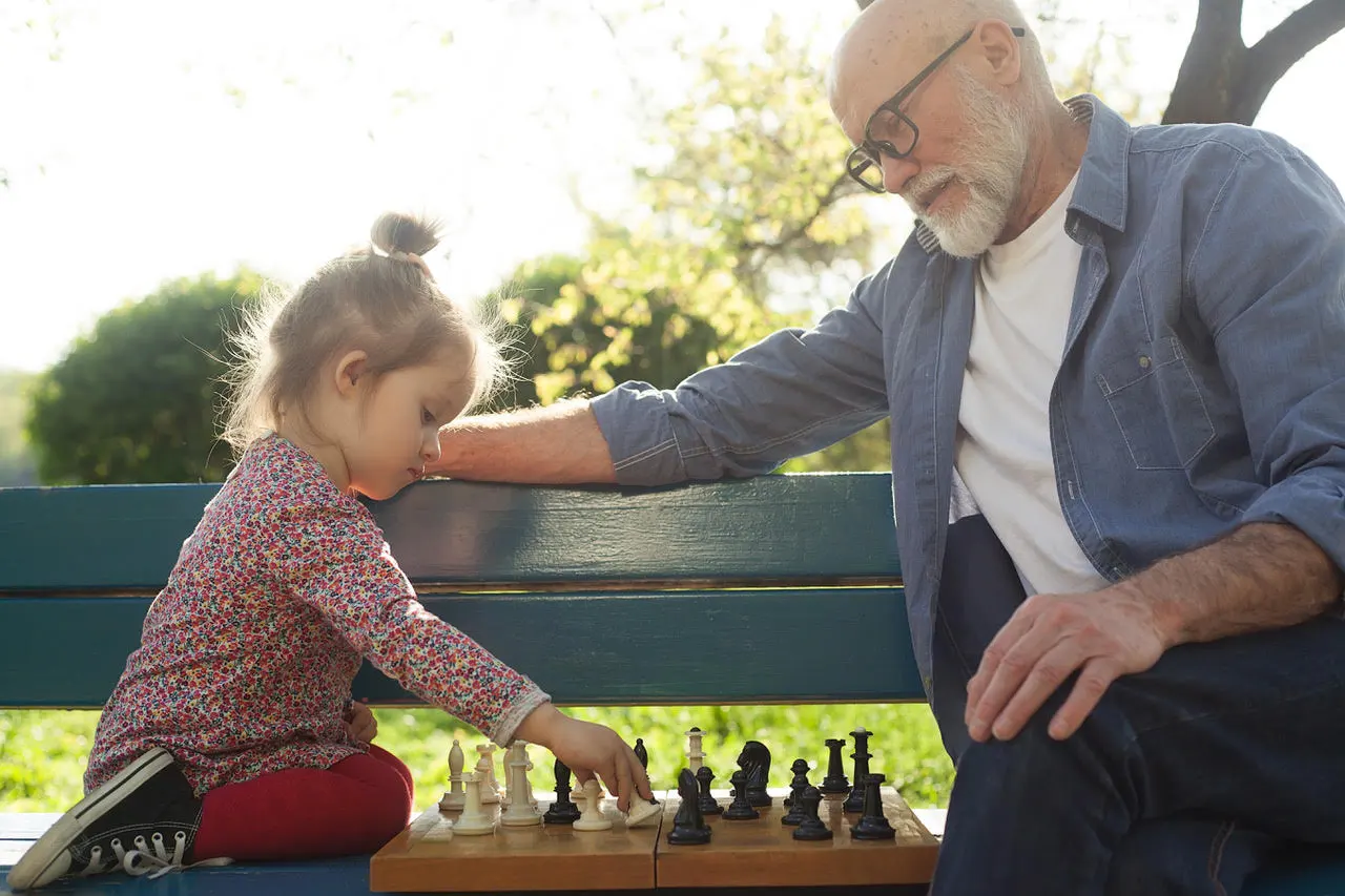Elderly man and young girl playing chess.